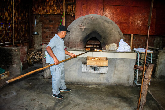 Baker cooking bread the traditional way, in a dome-shaped wood-fired oven, in Chilca - Peru