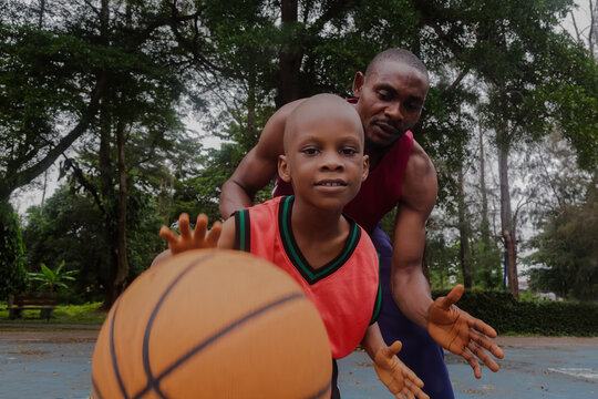 Little boy bouncing basketball with father
