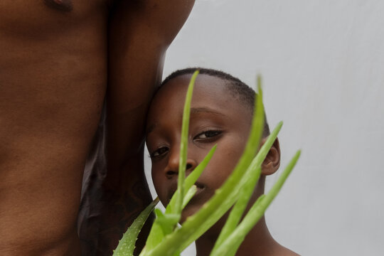Boy resting head on fathers arm with an aloe vera plant in front