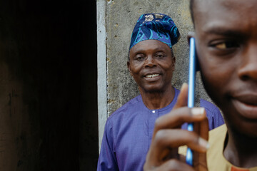 Elderly father in background and young adult son on a phone call