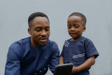 Nigerian father and son smiling at phone