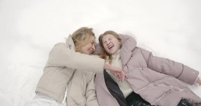 Happy mother with teenage daughter lying in snow