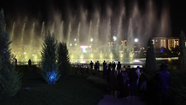 Autumn, 2022 - Tashkent, Uzbekistan - Musical fountain in Tashkent City. People watch the performance of the musical fountain in the evening. Large fountain with evening illumination.
