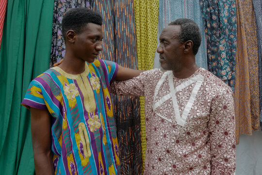 Nigerian father and son side by side looking at each other 