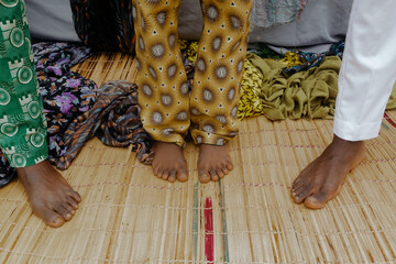 Nigerian boys standing bare-feet on mat dressed in ankara