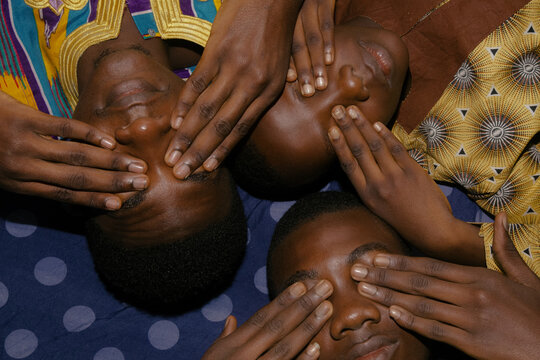 Close up of Nigerian boys with hands covering eyes