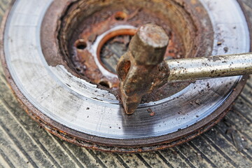 Beating off rust with a hammer from an old rusty brake disc