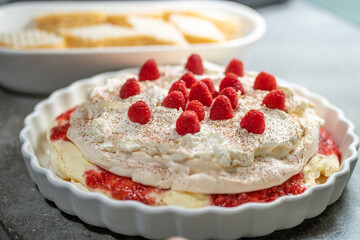 Home-made European style desserts with fresh raspberries on white ceramic serving trays against a dark grey background.