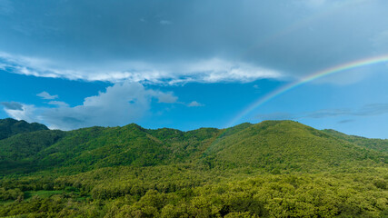 Fototapeta na wymiar Rainbow on Sky in the mountains, Panorama of flying in a Nature rainbow in the rain, aerial view of Rainbow in mountain , Rainbow in the Mountains Puffy Clouds After the Rain