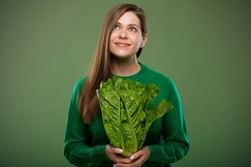 Smiling woman holding romaine lettuce salad looking up. Advertising female portrait on green.