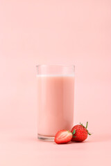 Glass with tasty strawberry smoothie / strawberry milk on pink background.
