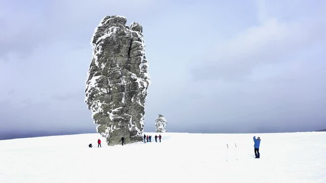 Flight near to Manpupuner in winter, Pillars of weathering (Mansi blockheads) in the snow - a geological monument on Mount Man-Pupu-ner "small mountain of idols" in full growth compared to people