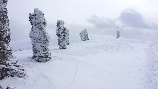 Flight on a copter straight ahead with the snow-covered stone blocks of Manpupuner in winter. Aerial view on a drone Pillars of weathering (Mansi blockheads) in the snow - mountain Man-Pupu-ner "