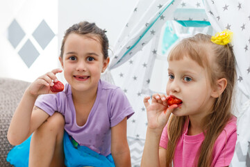 Obraz na płótnie Canvas two little girls eating strawberries