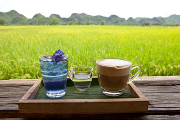 Coffee and Butterfly Pea Tea on the rice fields background. Beautiful Nature in Kanchanaburi, Thailand. Coffee with a View.