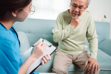 Obraz premium Asian caregiver talking senior male patient checkup in living room at home. Older elderly man consults after physical therapy. Nurse assistance rescue concept.