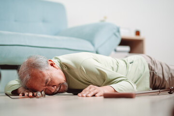 Fototapeta premium Asian senior man falling on the ground with walker in living room at home. Elderly older mature male having an accident heart attack for emergency help support from hospital. Insurance health care.