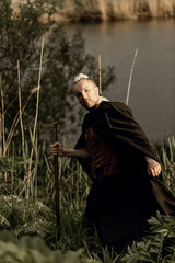 A young man with an interesting depicts a Viking with an ax in an unreliable stylized modern costume