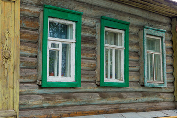Fototapeta na wymiar The beautiful old windows with beautifully designed platbands window on an old wooden house in the city of Tula