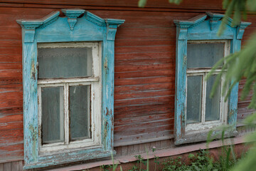 Fototapeta na wymiar The beautiful old windows with beautifully designed platbands window on an old wooden house in the city of Tula.