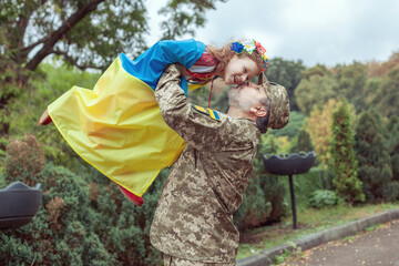 Ukrainian soldier is holding his daughter in his arms.