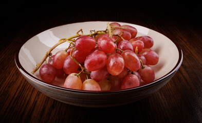 A bunch of ripe red grapes lies in a plate . Beautiful red grapes.