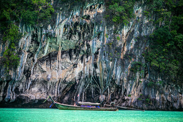 Image of boats and cliffs against an emerald green sea background.