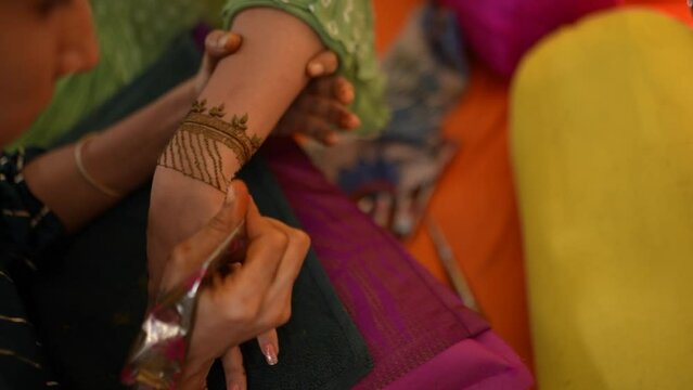 Artist paints mehndi on a woman's hand