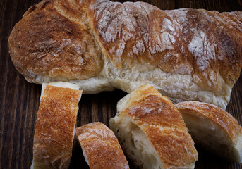 Sliced fresh baguette with herbs and spices on a wooden table. Art bread.