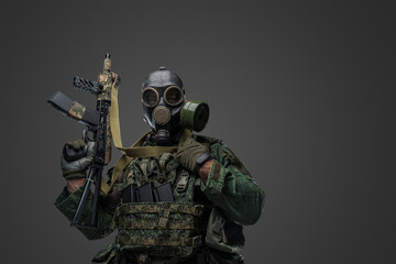 Studio shot of russian soldier dressed in protective uniform and gas mask against gray background.