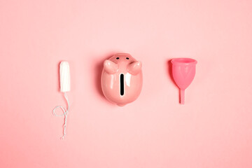 Piggy bank with tampon and menstrual cup on a red background. Save money with reusable feminine hygiene products.