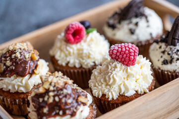 Tasty sweet muffins with mascarpone creme and chocolate, raspberry and blueberry. Fresh home baked sweets with fruit. Placed in wooden box.