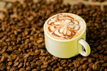 cup of cappuccino on a table with coffee beans
