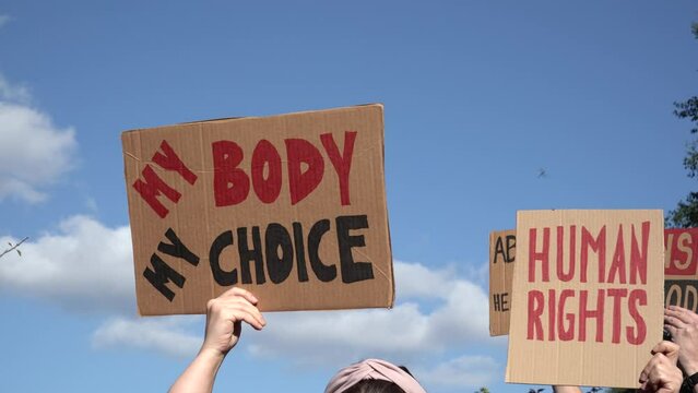 Protesters holding signs My Body My Choice, Human rights, Abortion Is Healthcare, Bans Off Our Bodies. People with placards supporting abortion rights at protest rally demonstration.