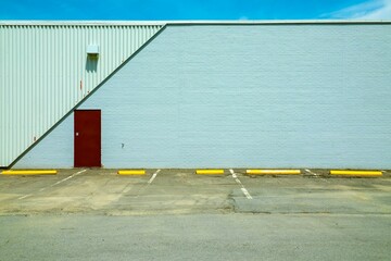Outdoors shot of a garage and a mild-colored wall and a burgundy door with a parking lot
