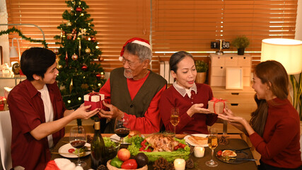 Young couple celebrating Christmas or New Year with grandparents at home. Holidays and celebration concept