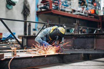 Worker using electric wheel spark grinding on metal steel is part of beam structure