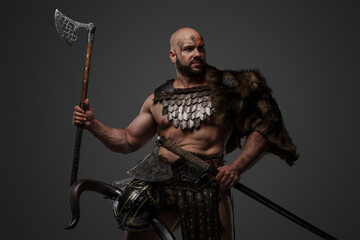 Shot of assaulting viking with muscular build and fur holding two axes.