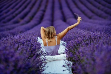 A middle-aged woman sits in a lavender field and enjoys aromatherapy. Aromatherapy concept,...
