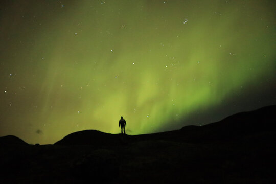 silhouette of a person facing northen lights