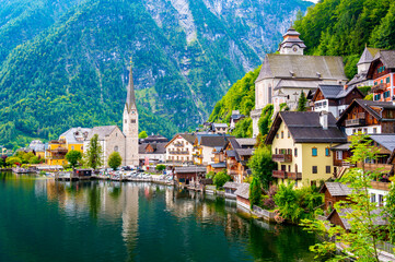 Famous view of Hallstatt city and church near the lake. Mountains in the background. Summer rainy...