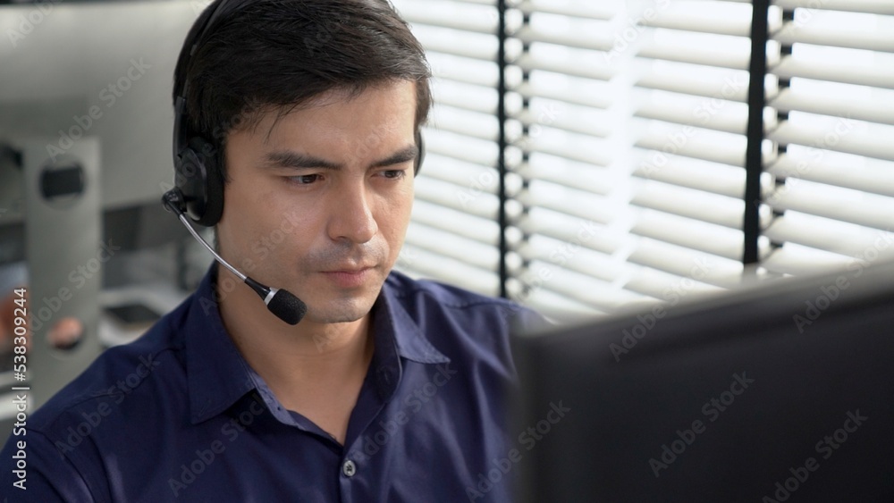 Aufkleber young competent asian male call center agent working at his computer while simultaneously speaking w