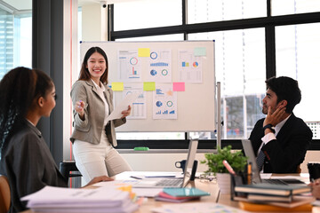 Confident young female project manager explaining new project idea or corporate business plan at meeting