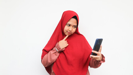 Asian woman in hijab confused while looking at smartphone