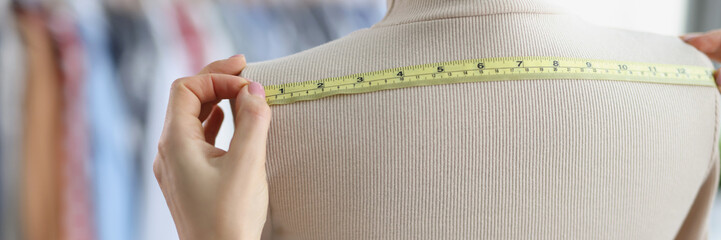Seamstress with measuring tape measures on a mannequin