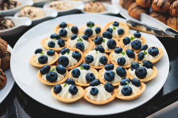 Catering table, beautifully decorated banquet with variety of with different food snacks appetizers on corporate birthday party event or wedding celebration, canape, salad, delicatessen setting
