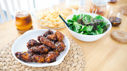 Korean spicy fried chicken and vegetables with coffee on a wooden table.