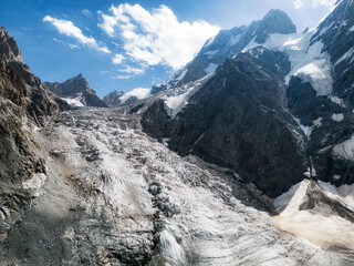 Atmospheric landscape with large snow mountain range in sunny day. Glacier and icefall in bright sun among sharp rocks.