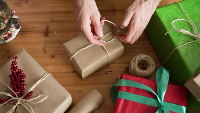 Man wrapping Christmas gift with twine and gift tag.. Christmas or New year DIY packing Concept. 