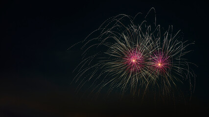 Close up of fireworks explosion with pink stars and yellow fountains. Isolated on black night sky. Ideal for Sylvester and New Year.